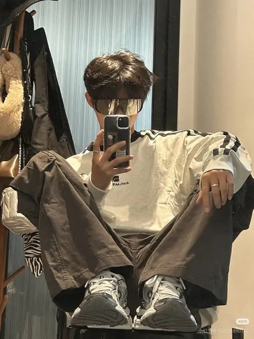 16 Trong gương lớn cậu trai ngồi dạng chân với bộ đồ ánh kim hơi bóng tạo cảm giác ngầu và dứt khoát ánh sáng tối làm vẻ nam tính đậm hơn rất hợp tinh thần trai đẹp lạnh lùng đang được ưa chuộng