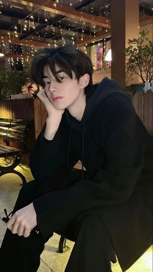 20 Chàng trai mặc đồ đen ngồi trong góc quán ánh đèn vàng tạo lớp bóng sâu quanh gương mặt cách tựa tay và nghiêng đầu làm ảnh mang hơi hướng ảnh chàng trai điển trai có chiều sâu hơn kiểu tạo dáng thường thấy