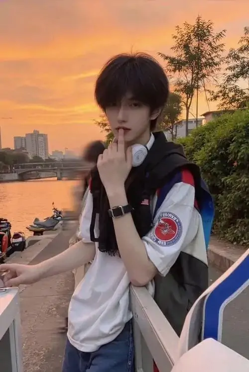 21 Khung hình mỹ nam đứng giữa nền trời cam tím lúc chiều tà với đồng phục tối và vai đeo túi tạo cảm giác vừa trẻ vừa rắn rỏi sắc trời phía sau khiến đường hàm rõ nét trở thành điểm giữ mắt rất mạnh