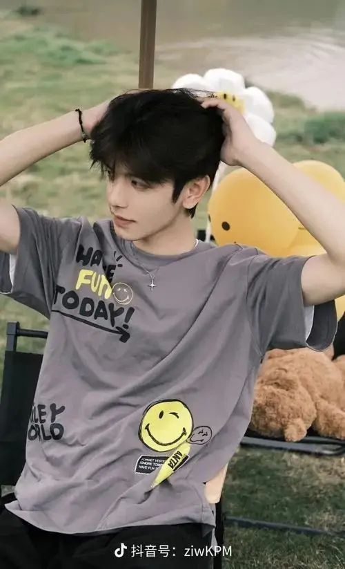 22 Cậu trai mặc áo xám ngoài trời giơ tay lên tóc dưới nắng nhẹ tạo khung cảnh thoáng và tươi dáng đứng nghiêng nhẹ cùng gương mặt sáng làm ảnh toát lên vẻ thư sinh mà không mất đi chất nam tính