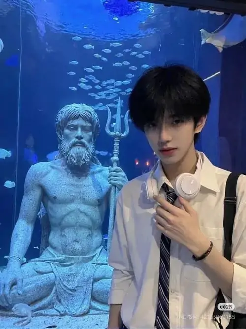 23 Ảnh soái ca trong không gian xanh lam của bể trưng bày với tượng phía sau và động tác chạm tay trước ngực tạo chiều sâu thị giác rõ rệt màu ảnh lạ mắt giúp nét thanh tú trên gương mặt nổi lên mạnh hơn