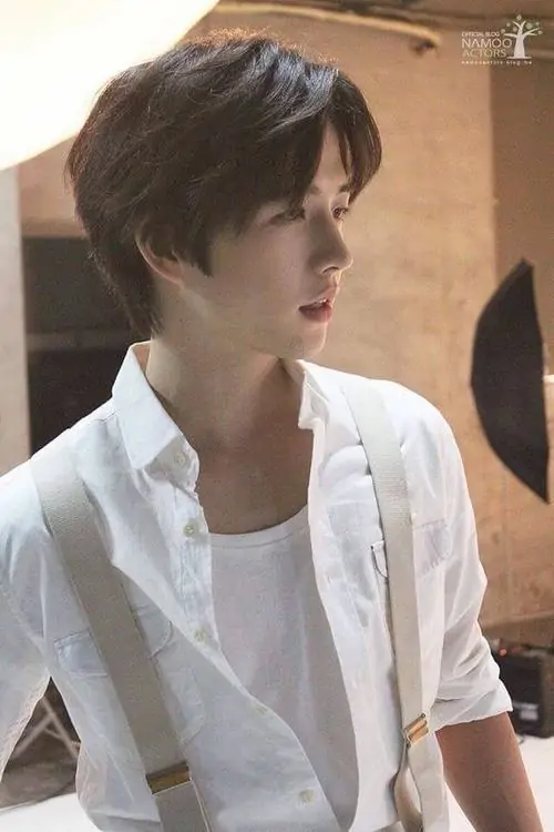 31 Khoảnh khắc nam thần trong sơ mi trắng với dây đeo vai đứng dưới ánh đèn ấm tạo vẻ thư sinh trưởng thành cùng lúc góc mặt nghiêng và cổ áo mở nhẹ làm khung hình có độ cuốn riêng khá rõ