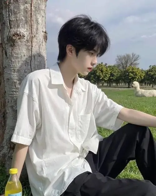 35 Ảnh mỹ nam mặc sơ mi trắng ngồi ngoài bãi cỏ cạnh chai nước nhỏ với tư thế thả lỏng và mắt nhìn xa bức hình tạo cảm giác chậm rãi nhưng vẫn chắc nhờ bờ vai rộng và vẻ gần gũi