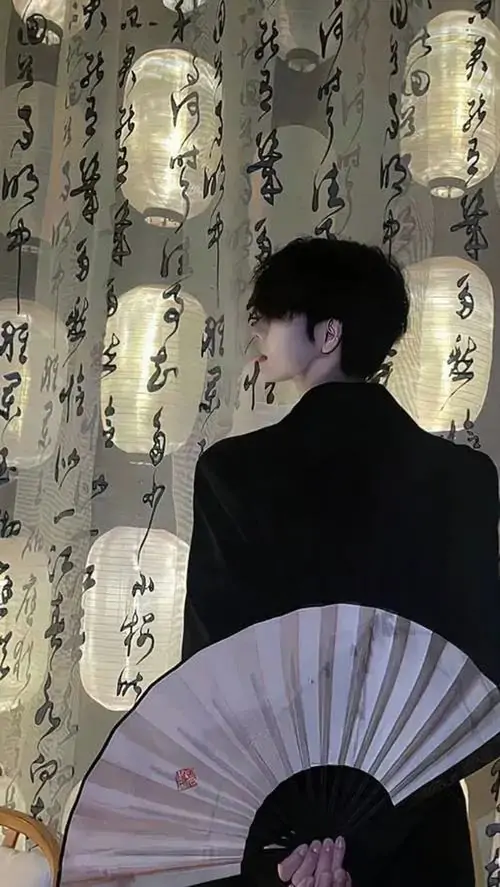 3 Hình chàng trai chụp nghiêng trong không gian rèm hoa cũ với chiếc quạt xếp cầm thấp trước người tạo cảm giác kín đáo và lạnh lùng ánh sáng mờ làm nổi bật đường nét rõ ràng cùng vẻ đẹp thư sinh rất cuốn