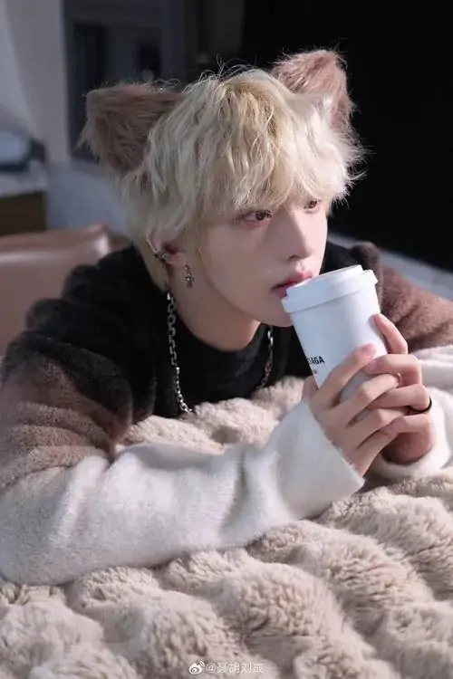 39 Hình cậu trai tóc sáng ngồi trong chăn mềm tay cầm cốc đồ uống nóng giữa ánh sáng tối ấm tạo cảm giác thư giãn và kín đáo dù khung hình nhẹ nhàng phong cách chỉn chu vẫn hiện lên rất rõ