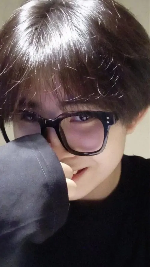 15 Ánh đèn thấp và phông tối làm bức cận cảnh thêm tập trung vào gương mặt, chàng trai đưa tay chạm môi, kính to và tóc nâu phủ nhẹ trán khiến ảnh chàng trai đeo kính mang nét bí ẩn, lạnh lùng nhưng có chiều sâu