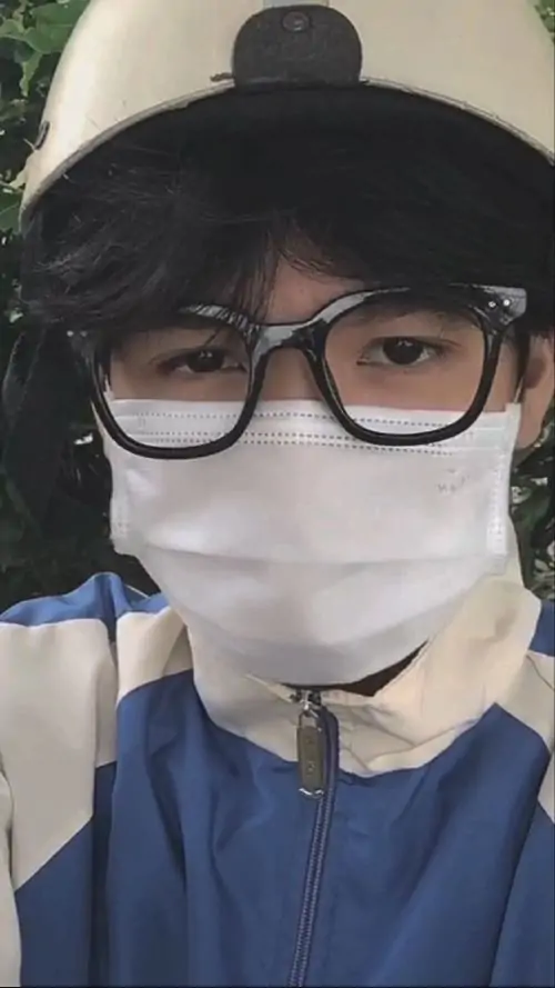 46 Ảnh soái ca kính cận đi giữa ngõ nhỏ có dây đèn treo cao, chàng trai mặc cardigan mỏng và cầm máy ảnh, bước chân chậm cùng nụ cười nhẹ làm khung hình có sức sống, hợp gu người mê ảnh chân dung nam giản dị