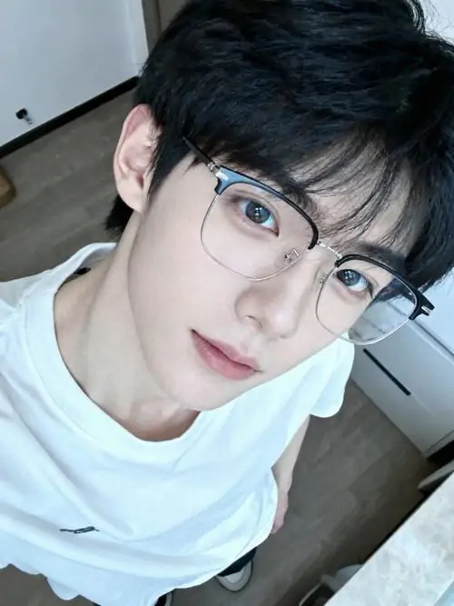 48 Hình nam thần kính cận giữa khu chợ đêm với bảng đèn mờ phía sau, chàng trai mặc áo khoác bomber và nhìn ngang, màu ảnh tương phản vừa phải tạo không khí hiện đại, đồng thời giữ được nét bí ẩn rất ổn định