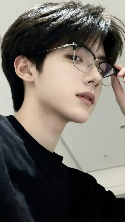 31 Ảnh chàng trai đẹp đeo kính ở thư viện với sơ mi trắng và tay áo xắn nhẹ, chàng trai đứng giữa kệ sách, ánh đèn vàng phủ mỏng lên tóc, nam thần học đường hiện ra rõ qua vẻ chăm chú và dáng đứng chỉn chu