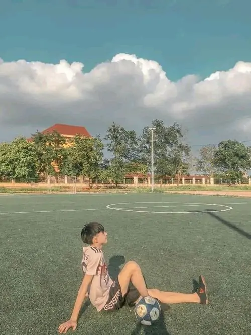 25 Ảnh boy phố k8 nhìn từ phía sau giữa bãi cỏ và nền trời nhạt, dáng đứng nhỏ và kín đáo tạo cảm giác riêng tư, kiểu chụp không lộ mặt nhưng vẫn giữ được vẻ trẻ trung và nét trong sáng dễ mến