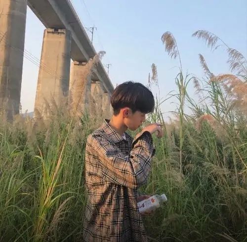 30 Chàng trai mặc áo số rộng đứng cạnh tường gạch cũ, một tay đưa lên phần mặt như đang né ống kính, bức ảnh hợp gu ảnh trai đẹp che mặt vì vừa có chất đường phố vừa giữ độ bí ẩn