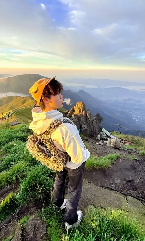 5 Khoảnh khắc hot boy học đường trên mỏm đá cao với áo vàng nổi bật giữa nền mây núi, dáng đứng hơi khom như đang nhìn xuống cảnh xa, bức ảnh mang cảm giác cá tính và tự nhiên hơn kiểu chụp dàn dựng thông thường
