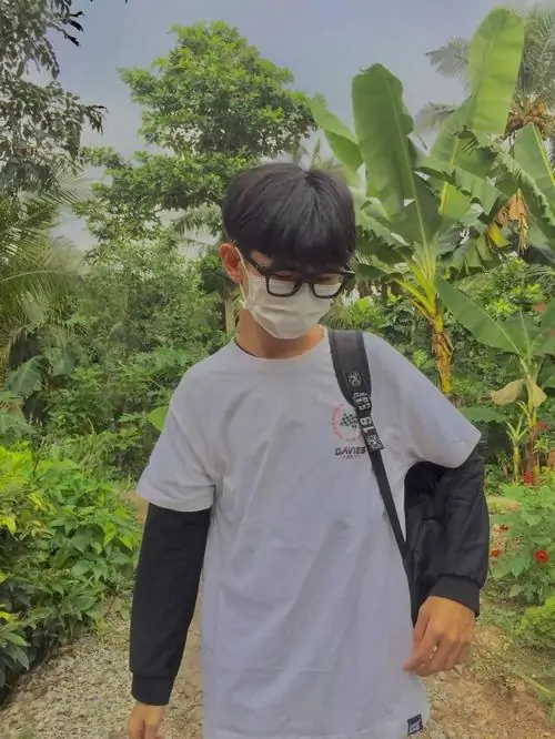 14 Cậu trai mang kiếng mặc áo xám tay dài đen balo đứng giữa cây chuối thể hiện kết hợp đồng phục trường với đồ phố và chiều cao vượt trội của nam sinh lớp 11.