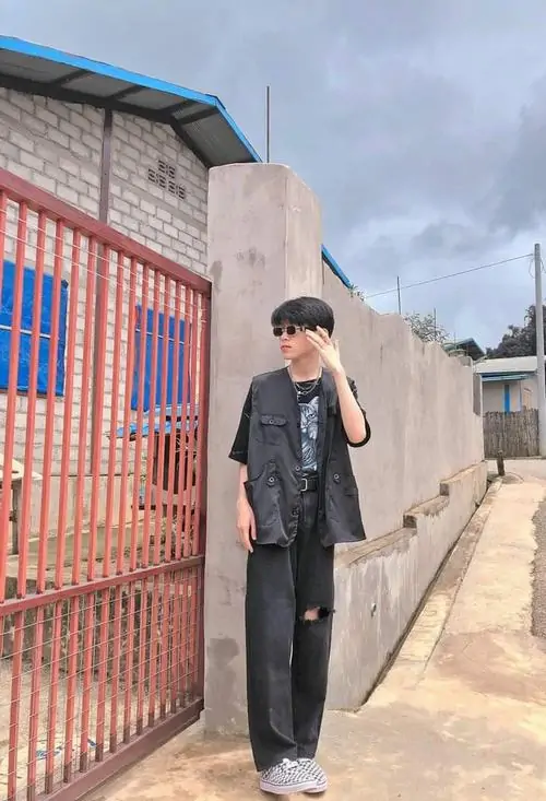 15 Cậu trai k9 đứng cạnh cổng sắt với áo vest đen quần tối màu toát lên thần thái cuốn hút và gu thời trang của boy phố k9.