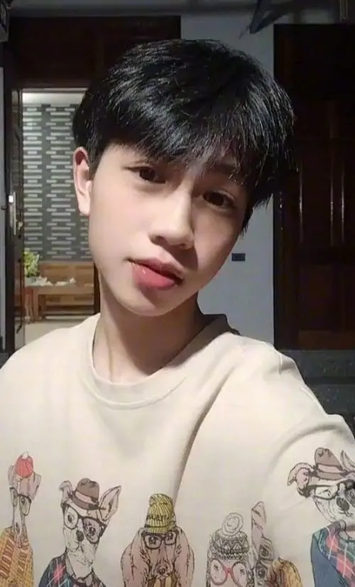 31 Nam thần lớp 11 tựa lưng vào tường ngoài trời với áo phông trắng in họa tiết toát lên thần thái cuốn hút và gu thời trang hoodie varsity của chàng trai k9.