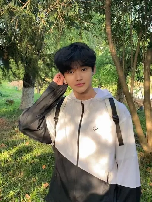 4 Cậu trai trẻ vuốt tóc trong jacket trắng đen giữa cây cối cho thấy jawline sắc nét cùng chiều cao bứt phá mạnh của hot boy gen z đang chuyển mình.