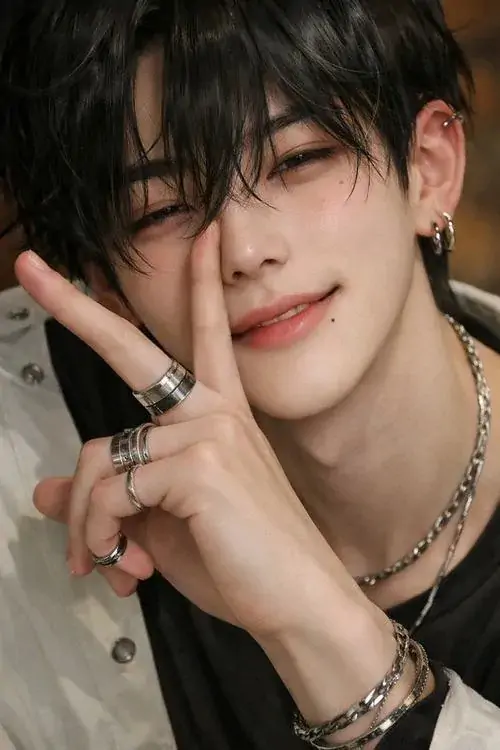 14 Chàng trai tóc đen cười khẽ trước máy, tay giơ dấu chụp ảnh và phụ kiện cổ tay làm điểm nhấn, khung hình sáng vừa đủ để tôn gương mặt, mang lại cảm giác dễ gần, đẹp và vẫn có độ cuốn hút rất nam tính