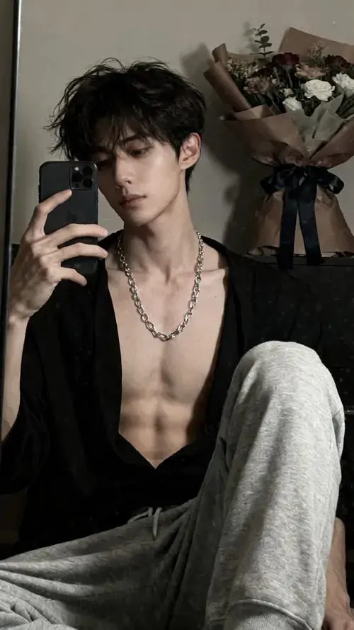 15 Khoảnh khắc trai đẹp trong gương cho thấy anh chàng mặc sơ mi mở sâu, ngồi thả lỏng trên ghế với dây chuyền mảnh, bối cảnh phòng tối giúp thần thái nổi bật hơn, gợi vẻ hấp dẫn trưởng thành của một mỹ nam ít lời