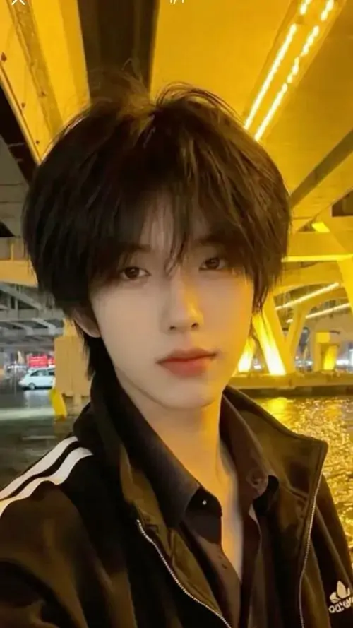 3 Hình chàng trai đứng dưới nền đèn vàng, tóc rủ che trán và gương mặt góc cạnh hiện rõ trong cận cảnh, sắc thái trầm khiến bức ảnh mang vibe nam thần lạnh lùng, vừa bí ẩn vừa cuốn mắt ngay từ lần nhìn đầu