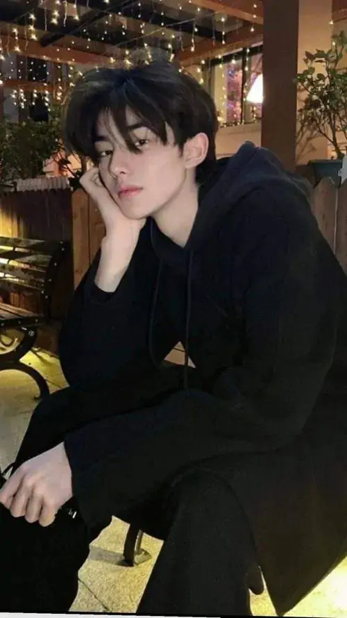 8 Anh chàng ngồi tựa ghế trong bộ đồ đen, tay chống mặt giữa nền sáng vàng dịu, biểu cảm ít nói tạo cảm giác gần mà khó chạm, bức ảnh giữ được khí chất trưởng thành và vẻ cuốn hút bền, nhìn lâu vẫn thấy rất đẹp