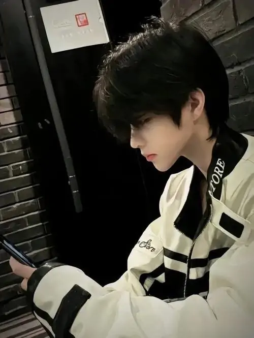 60 Người mẫu trẻ quay nửa mặt bên cửa kính cao tầng trong chiếc sơ mi đen mở cổ nhẹ tư thế thẳng lưng và tay đặt trong túi tạo khí thế kín mà mạnh gợi liên tưởng đến Song Kang ở nét trầm và cuốn