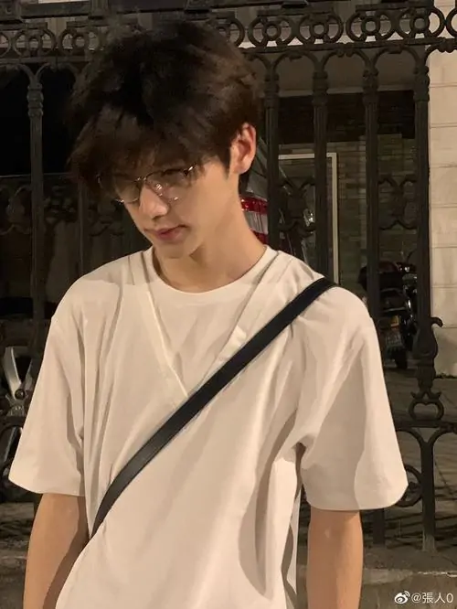 42 Cậu trai mặc áo trắng và đeo túi chéo đứng giữa hành lang hẹp với ánh đèn vàng kéo sâu vào nền sau tư thế thẳng lưng khiến vóc dáng săn chắc được tôn lên theo cách kín nhưng rất hiệu quả