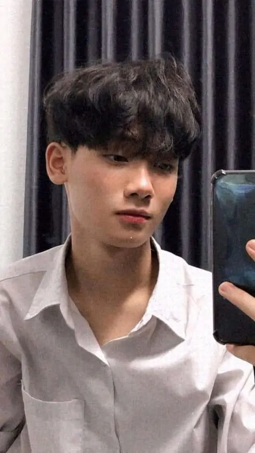 12 Chàng trai trong giai đoạn phát triển mạnh với chiều cao cao lớn dẫn đến dáng vẻ nam tính hơn khi mặc áo sơ mi trắng cầm điện thoại. Nam sinh lớp 10 Việt Nam toát lên sự kết hợp thư sinh và thể thao trong không gian indoor gần gũi.