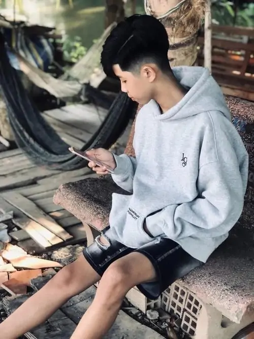 9 Khoảnh khắc thiếu niên với áo hoodie và phong cách giấu mặt bí ẩn khi ngồi ghế ngoài trời lúc chập tối. Nam sinh tuổi mới lớn Việt khoe chiều cao đột phá lên 1m80 và dáng vẻ năng động tràn đầy năng lượng.