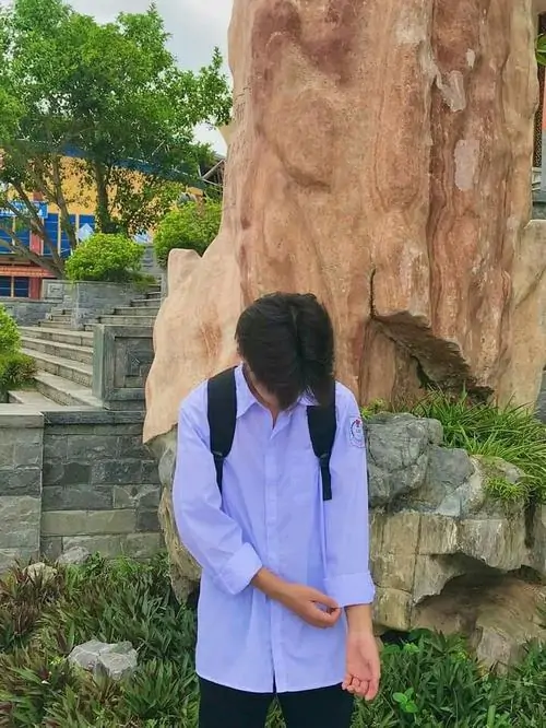 8 Một bạn nam ngồi thu mình, cúi đầu và dùng tay che mặt, tạo cảm giác trầm lặng, ánh sáng tự nhiên làm tăng chiều sâu cảm xúc cho ảnh trai đẹp lớp 7 che mặt