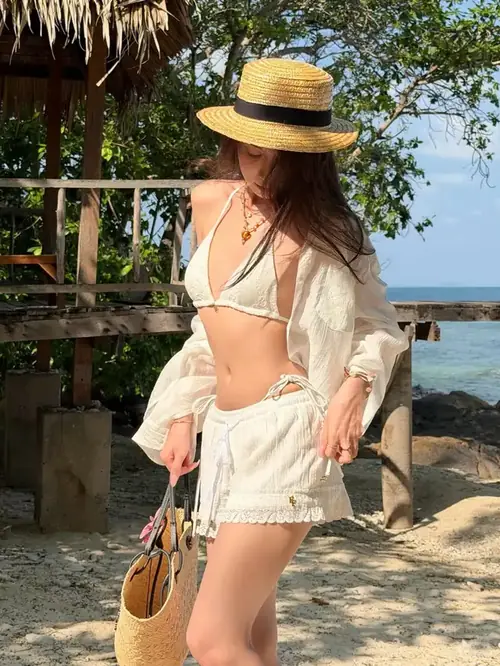22 Trên cầu gỗ, người đẹp quay lưng nhìn biển, tay cầm mũ và mái tóc dài rơi xuống vai.