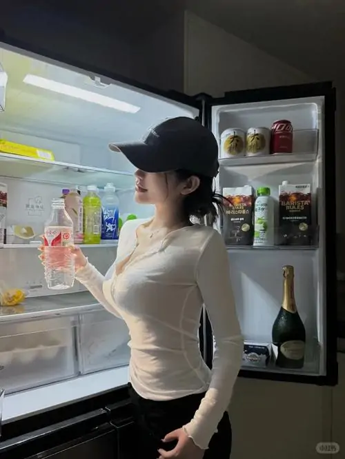 11 Chiếc váy đỏ ôm nhẹ vú to cân đối khi người mẫu đứng nghiêng bên bức tường màu sáng.