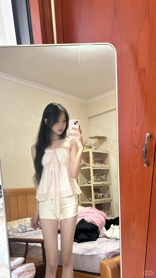 14 Chiếc áo sơ mi xanh nhạt được sơ vin cùng váy đen, cô gái cầm điện thoại và cười nhẹ.