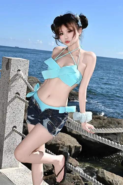 26 Bộ ảnh người mẫu biển cho thấy cô gái giữ khăn choàng bay nhẹ trong gió cạnh làn nước xanh.