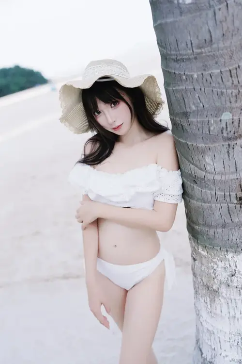 27 Giữa bãi biển vắng, cô gái chống tay lên hông, tóc buộc cao và ánh mắt nhìn chếch sang bên.