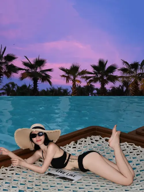 28 Bờ cát mịn bao quanh cô gái mặc bikini hồng, ngồi co một chân và chống tay phía sau.