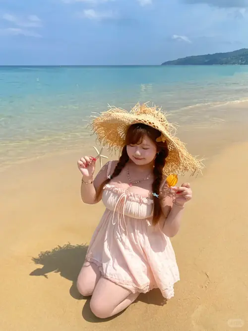 23 Một tay giữ vành mũ, cô gái mặc bikini cam đứng giữa bãi biển với nụ cười thoải mái.