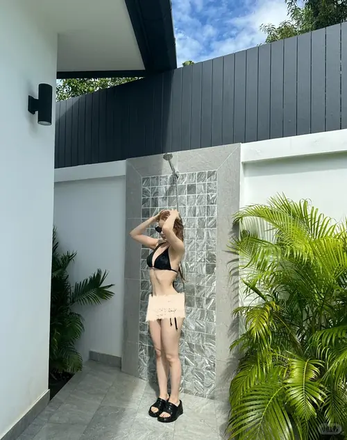 11 Chiếc điện thoại che mặt cô gái mặc bikini đỏ đang đứng nghiêng bên sóng với dáng vẻ thoải mái.