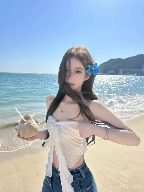 27 Nước biển chạm ngang đầu gối khi cô gái mặc bikini trắng bước chậm, tay vuốt mái tóc ướt.