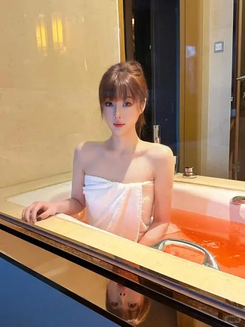 27 Rèm mỏng lay cạnh người mẫu đang ngồi bó gối, khăn lụa phủ thân và ánh mắt hướng xuống sàn.