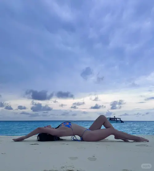 26 Trong hình người đẹp bên biển quay lưng, người mẫu mặc bikini đen và khoác sơ mi trắng mỏng.
