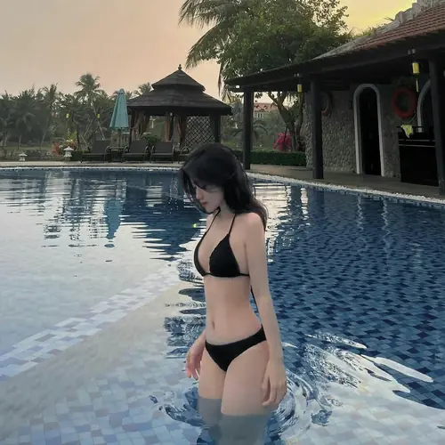 11 Tựa người trong hồ bơi resort, cô gái mặc bikini đen cúi mắt rất tự nhiên
