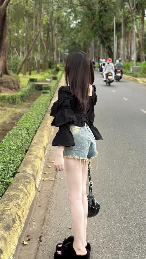 13 Hàng cây ven đường tạo nền xanh cho cô gái áo đen váy ngắn bước chậm
