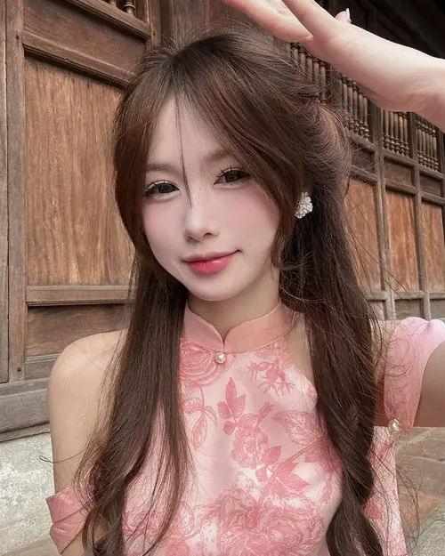 10 Trước vách gỗ nâu, cô nàng váy hồng nghiêng đầu với nụ cười quyến rũ nhẹ